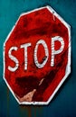 Old weathered stop sign on teal background