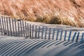 Old weathered wood fence along beach with long shadows from afternoon sunlight Royalty Free Stock Photo