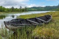 Old and weathered wooden boat wreck laying on the ground in beautiful norwegian landscape with mountains in the background