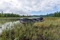 Old and weathered wooden boat wreck laying on the ground in beautiful norwegian landscape with mountains in the background.