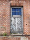 Old weathered wooden door with window in brick wall Royalty Free Stock Photo