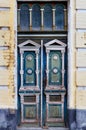 Old weathered wooden entrance doors with carved elements and a symmetrical pattern on the facade of an old house