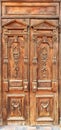 Old weathered wooden entrance doors with carved elements and a symmetrical pattern on the wings in the Ukrainian style