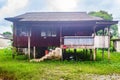 Old and weathered wooden house with pillars and stairs made out of bricks.