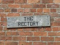 Old weathered wooden Rectory sign on a brick wall