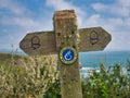 An old, weathered wooden sign indicating the route of the Wales Coast Path in Pembrokeshire, Wales, UK