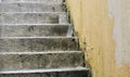 Old weathered, worn concrete outdoor staircase with painted brick wall to side