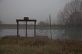 Old weir by the shore of a river on a foggy day in late autumn Royalty Free Stock Photo