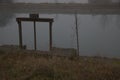 Old weir by the shore of a river on a foggy day in late autumn Royalty Free Stock Photo