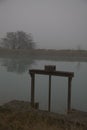 Old weir by the shore of a river on a foggy day in late autumn Royalty Free Stock Photo