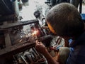 An old welder in a blue T-shirt use sunglasses. Selective focus on firework.