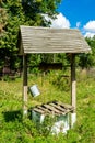 Old well with iron bucket on long forged chain for clean drinking water Royalty Free Stock Photo