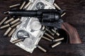 Old west Colt Peacemaker and US banknotes and silver certificates with silver dollar coins and .45 caliber revolver ammunitions Royalty Free Stock Photo