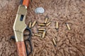 Old west lever-action rifle and ammunition with silver dollars coins on skins background