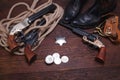 Old western revolver guns with sheriff badge and silver dollars with hat, rope and cowboy boots Royalty Free Stock Photo