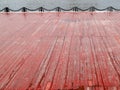 An old wet wooden embankment painted in red on a rainy spring day. Photo in perspective