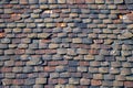 Old, wheathered roof with coloric ceramic roof tiles in bad condition color photo.