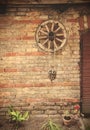 Old wheel and potted plant hanging on old brick wall