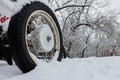 Old wheel with spokes in the snow. Close up vintage white car wheel over snow cover in winter time Royalty Free Stock Photo