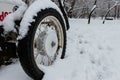 Old wheel with spokes in the snow. Close up vintage white car wheel over snow cover in winter time Royalty Free Stock Photo