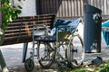 An old wheelchair stands near a bench on the lawn.