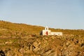 Old white abandoned Church Agios Ioannis on dramatic cliff on Kithnos Island, Greece, seen from the sea during golden hour