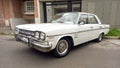 Old white AMC 1965 Rambler Classic 660 four door sedan parked in the street. Classic car show