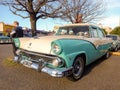 old white and aqua 1955 Ford Fairlane V8 four door sedan in a parking lot. Classic car show.