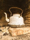 Old white battered kettle in a firebox