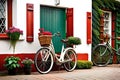 Old white bicycle with red and green flowers in front of a door vegetated generated Ai