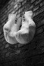 Old white boxing gloves hang on nail on brick wall with copy space for text. High resolution 3d render Royalty Free Stock Photo