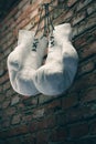 Old white boxing gloves hang on nail on brick wall with copy space for text. High resolution 3d render Royalty Free Stock Photo