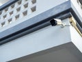 Old white CCTV camera hanging at the corner at the outdoor on concrete building. Royalty Free Stock Photo