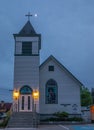 An old white christian church in rural Canada at nightfall. Wooden chapel with night lights Royalty Free Stock Photo