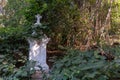 An old white cross surrounded by trees and woods