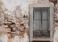 Old white damaged stone wall with ruined plaster and vintage window