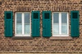 Old white framed windows on mediterranean house out of brick walls with green shutters Royalty Free Stock Photo