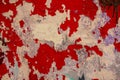 Old white gray battered concrete wall with peeling bright red paint. rough surface texture Royalty Free Stock Photo