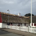 An old white house in Denmark, with a straw roof, in a village with a window with old glasses, a road.