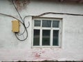 An old white house with a window and electrical wires. Royalty Free Stock Photo