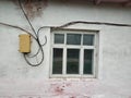 An old white house with a window and electrical wires. Royalty Free Stock Photo