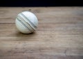 Old white leather cricket ball isolated against a wooden background Royalty Free Stock Photo