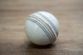 Old white leather cricket ball isolated against a wooden background Royalty Free Stock Photo