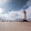 An old white lighthouse with a red roof on a sandy beach and a pathway infront with the sea and sky in the background Royalty Free Stock Photo