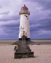 An old white lighthouse with a red roof on a sandy beach with the sea and sky in the background Royalty Free Stock Photo