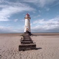 An old white lighthouse with a red roof on a sandy beach with the sea and sky in the background Royalty Free Stock Photo