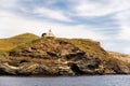 Old white lighthouse Akra Tamelos on majestic cliff on Kea Island, view from the sea with blue sky on sunny day, Greece Royalty Free Stock Photo