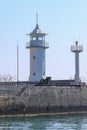 An old white lighthouse and an old cannon on a rocky promontory. In the background is a calm blue sea and sky. Yalta Royalty Free Stock Photo