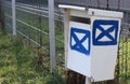 Old white metal post box letterbox, mailbox stand close near wire fence for send letter