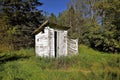 Old white outhouse in the woods